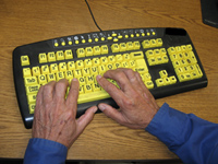 Low vision rehabilitation courses; Hands typing on a keyboard with black letters on yellow keys